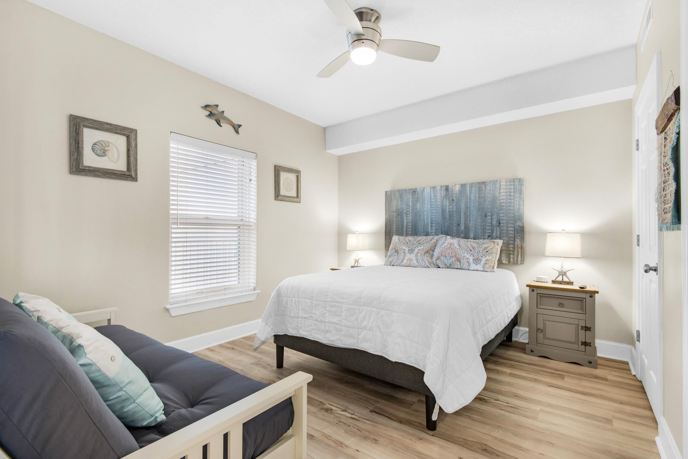A bedroom with a bed, a nightstand, a chair, and a ceiling fan.