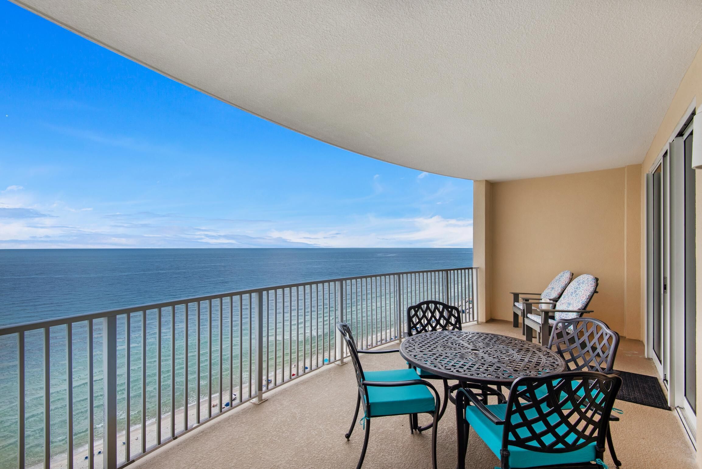 Un balcon avec une table ronde et des chaises, donnant sur une plage et l’océan.