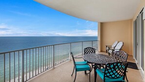 Ein Balkon mit rundem Tisch und Stühlen, mit Blick auf einen Strand und den Ozean.
