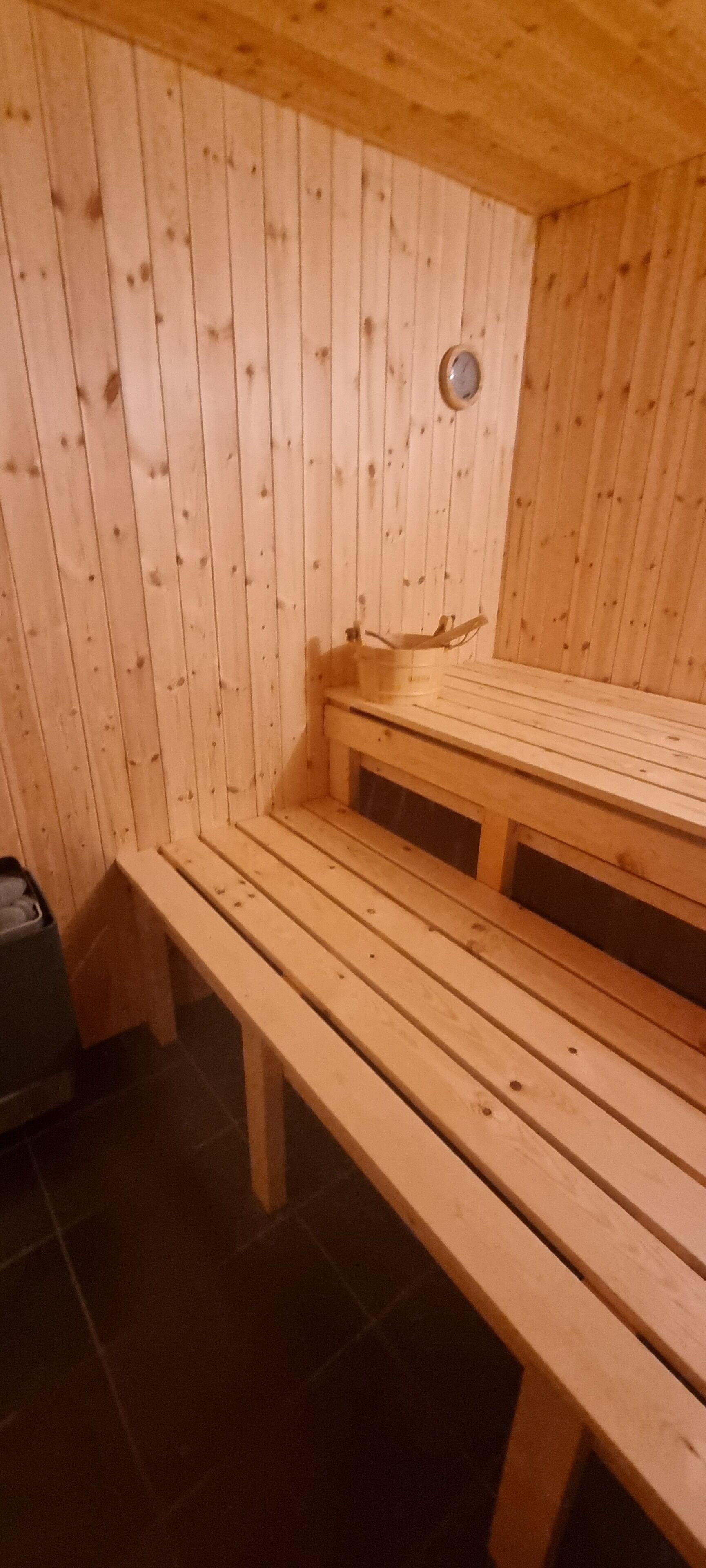 Un sauna en bois avec des bancs et un banc au sol.