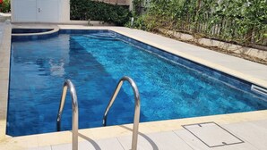 A rectangular swimming pool with clear blue water, surrounded by a tiled deck and a stone wall. - Fab Sea&Mountain View Villa Close to the beach (Gialia)