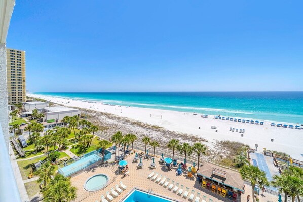 A resort with a pool, lounge chairs, and a beach view.