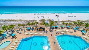 A beachside hotel with two large swimming pools, sun loungers, and palm trees. - The Summit 818 (Panama City Beach)