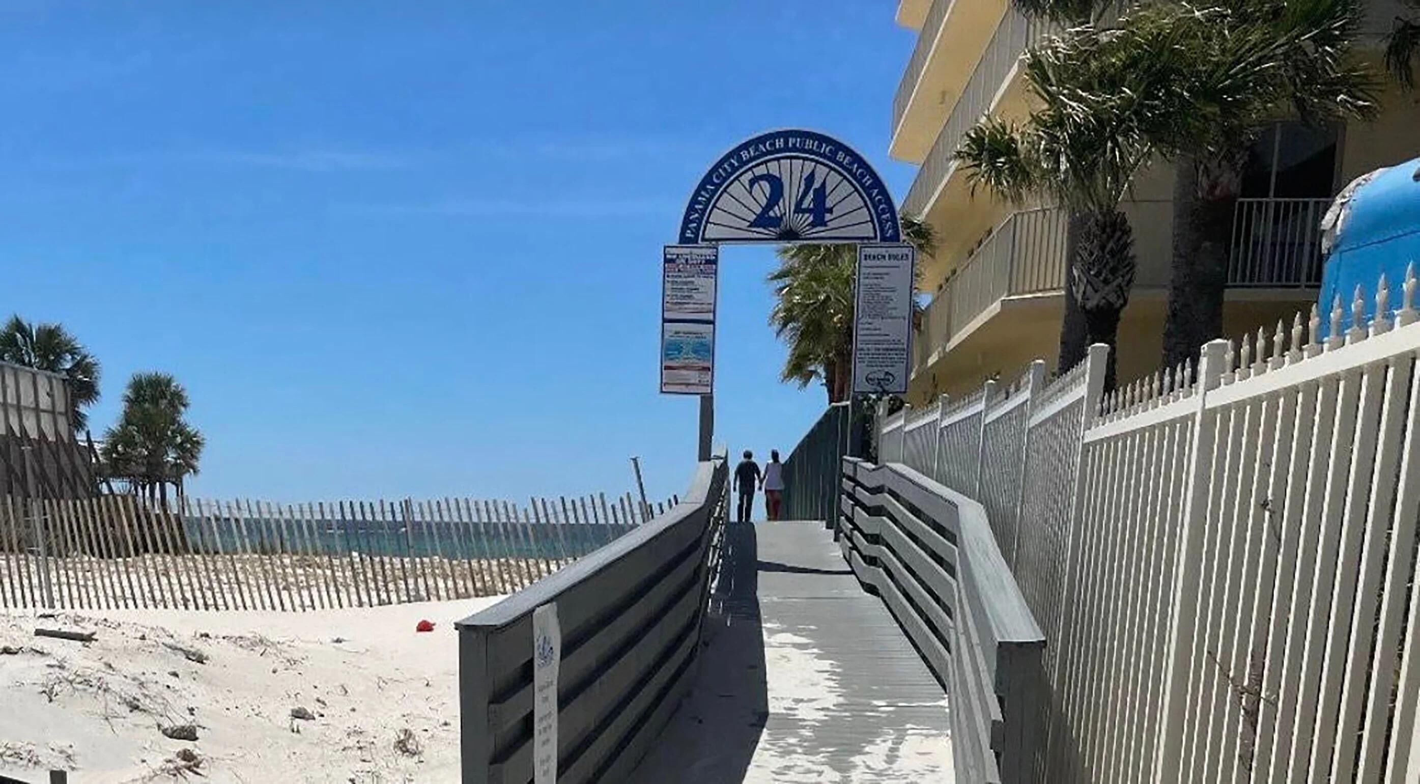 A pathway leading to a beach area with a sign indicating '24 Hour Beach Access'.