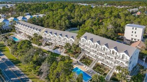 A resort with multiple-story buildings, a swimming pool, and a road running alongside. - Bluebonnet by the Beach (Santa Rosa Beach)