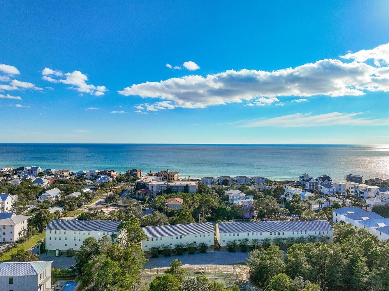 Un quartier résidentiel situé sur la côte, composé de plusieurs immeubles, avec un ciel dégagé et une vue sur l’océan.