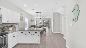A modern kitchen with white cabinets, a granite countertop, and a central island. - Bluebonnet by the Beach (Santa Rosa Beach)