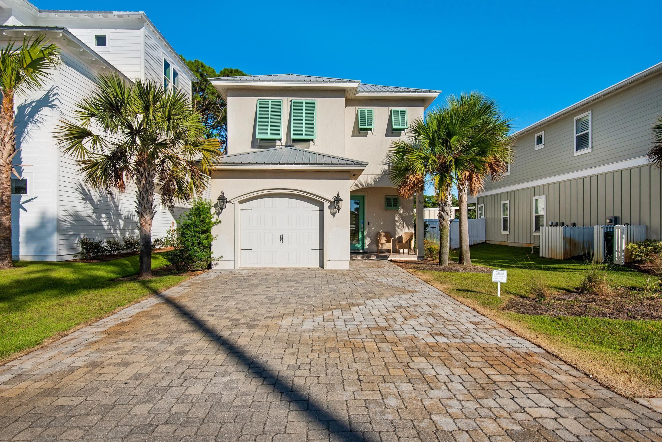 A two-story house with a paved driveway, palm trees, and a garage.