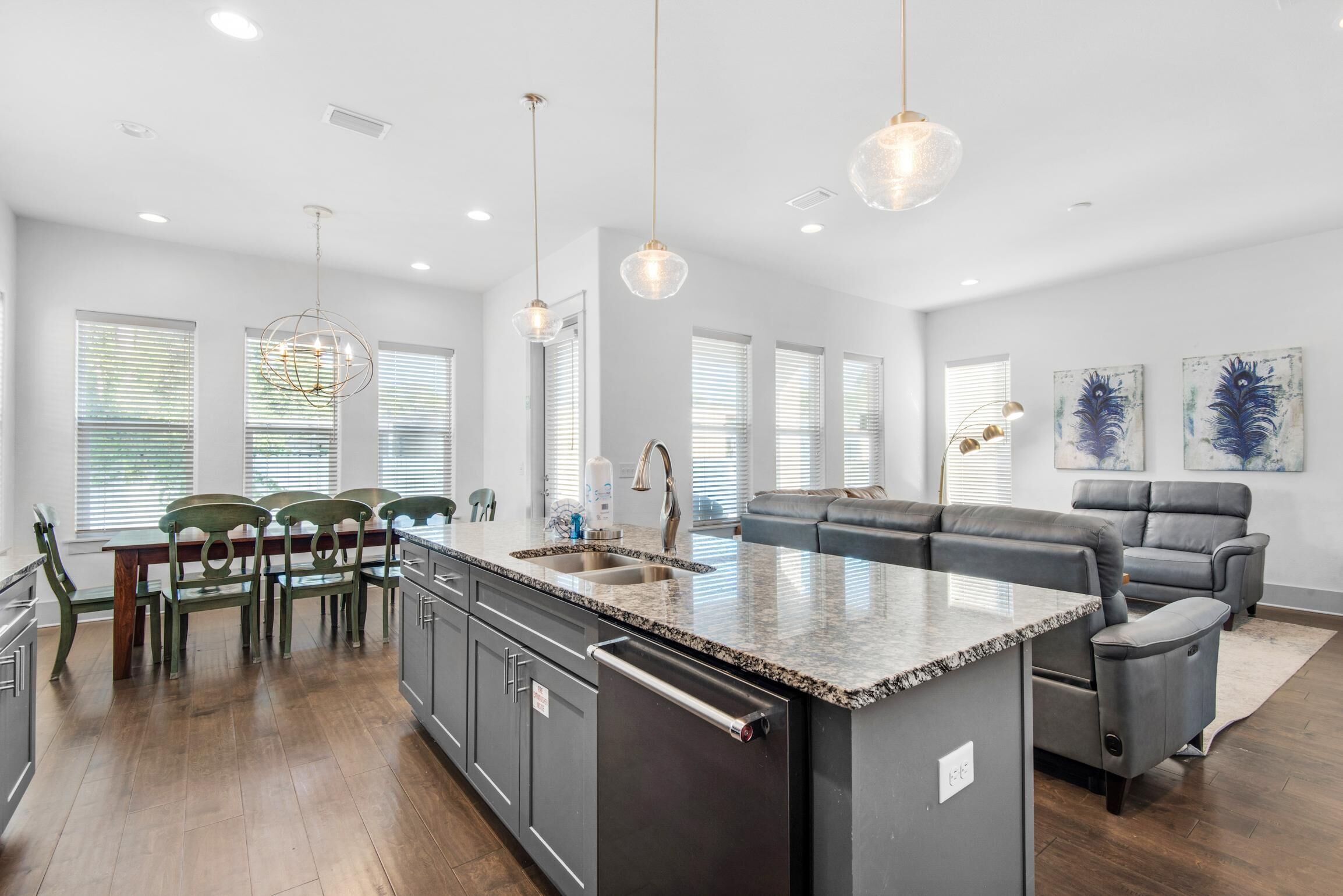 A modern kitchen with a central island, built-in appliances, and a dining area with chairs and a table.