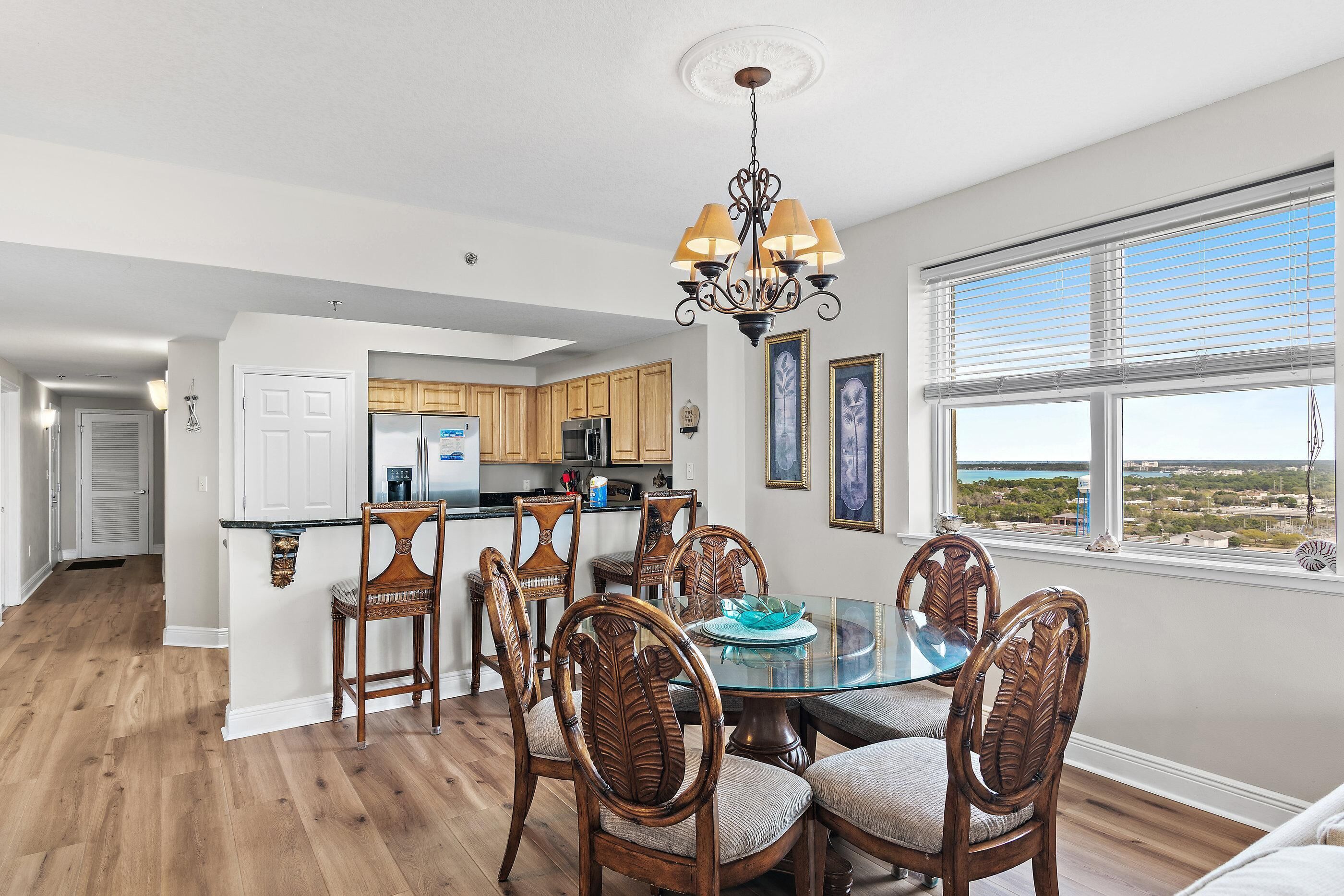 A dining area with a glass table, wooden chairs, and a chandelier.
