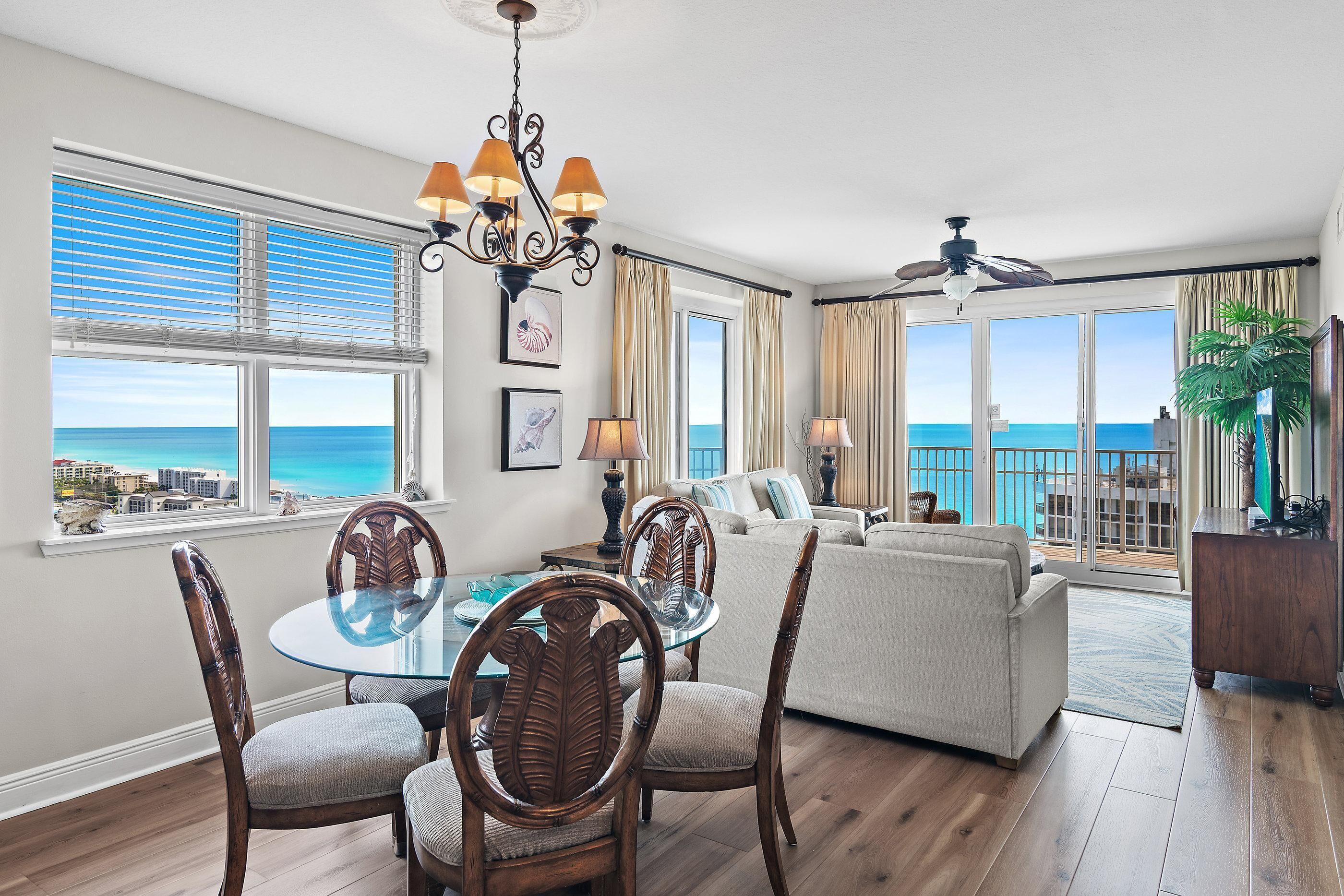 A spacious living area with a dining table, chairs, a sofa, and a view of the ocean.