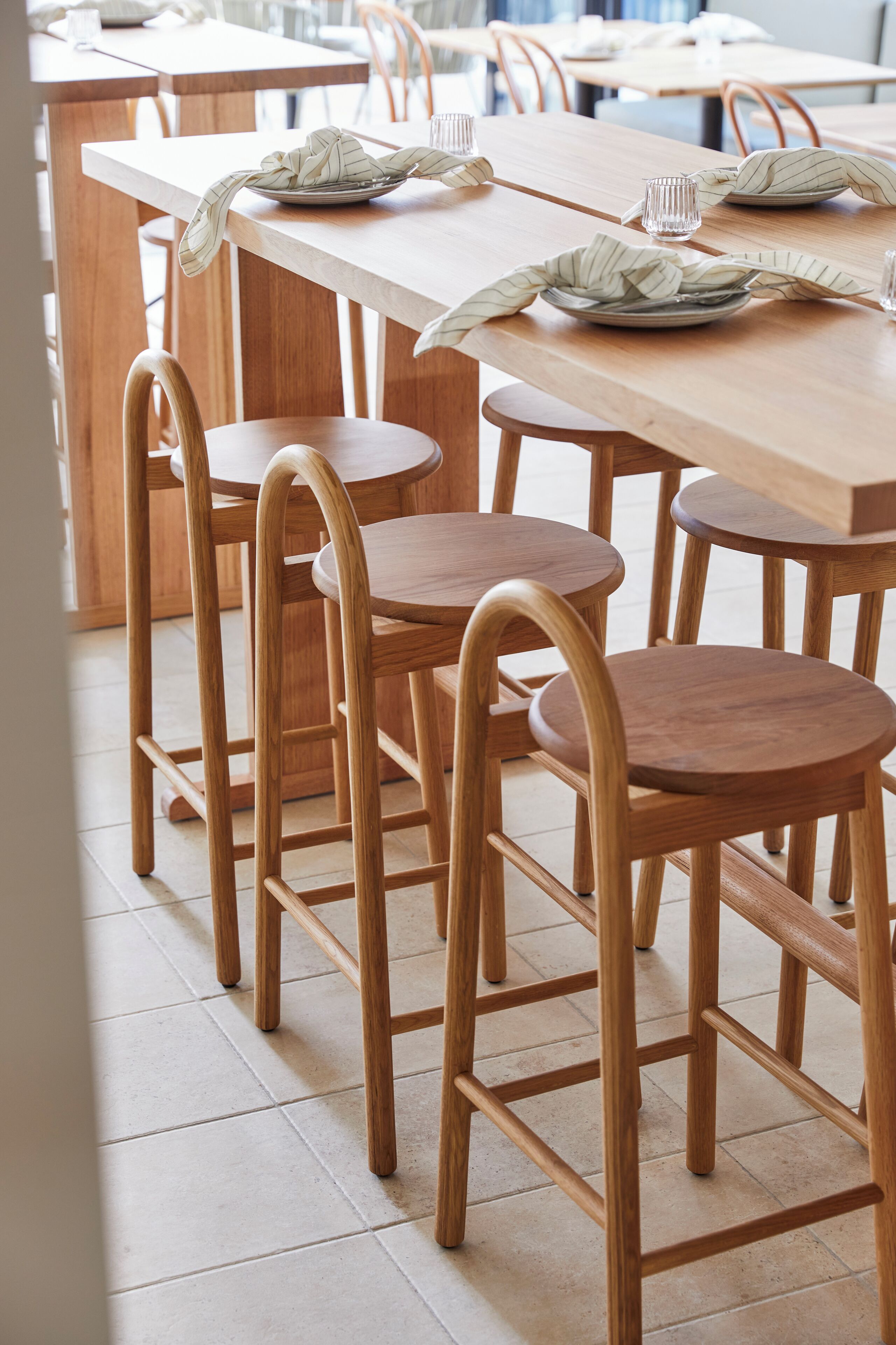 A dining area with wooden tables and chairs, arranged in a casual setting.