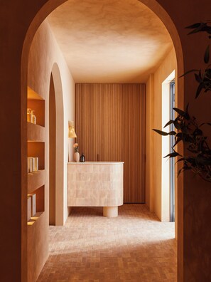 A spa-like bathroom with a large bathtub, wooden paneling, and a tiled floor. - The Clairfield Hotel (Mudgee)