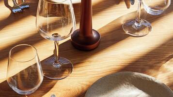 Una mesa de madera con cuatro copas de vino, dos cuchillos y un plato.