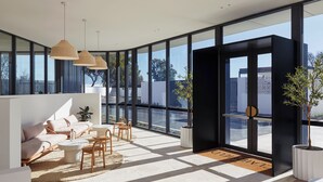 Un interior moderno con un sofá, sillas, una mesita de centro y un ventanal que ofrece vistas al exterior.