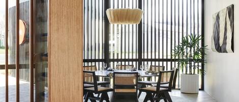Un comedor con una mesa redonda, sillas negras, una lámpara colgante y una planta en maceta.