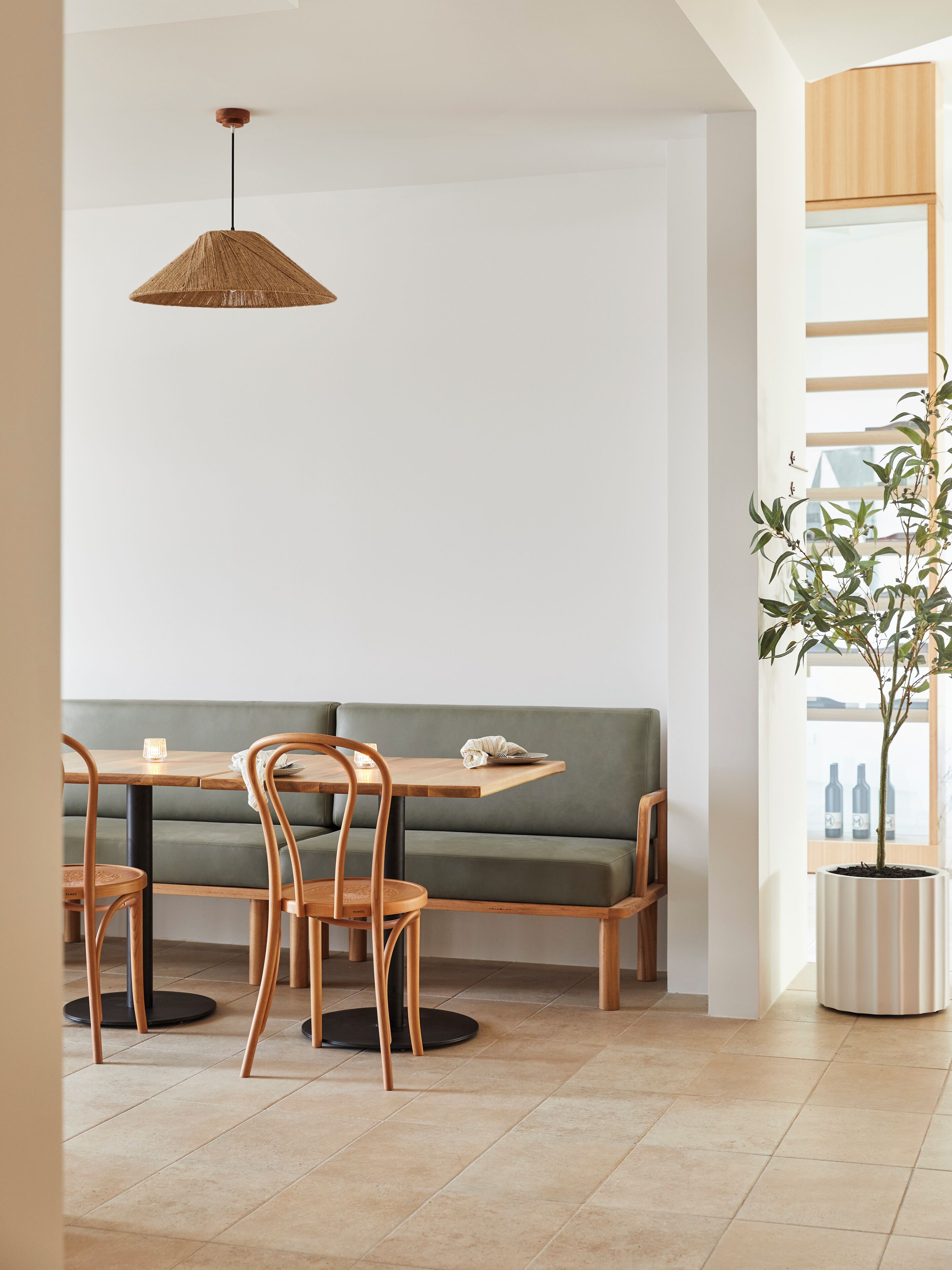 Un comedor con mesa de madera, sillas, un banco con cojín verde y una lámpara colgante.