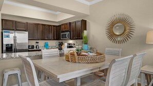 A modern kitchen with dark wooden cabinets, stainless steel appliances, and a decorative sunburst mirror. - Alerio D201 (Miramar Beach)
