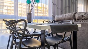 A modern dining area with a table and chairs, a potted plant, and a sofa in the background. - Inftour Apolo IV Apartamento (Calp)