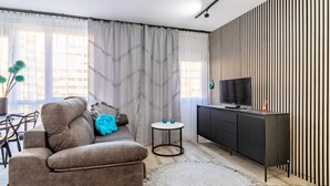 A modern living room with a sofa, a round rug, a TV on a black cabinet, and a striped wall. - Inftour Apolo IV Apartamento (Calp)