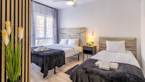 A hotel room with two beds, a ceiling fan, a nightstand with a lamp, and a window with curtains. - Inftour Apolo IV Apartamento (Calp)