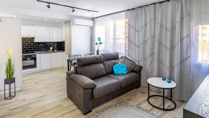 A modern living room with a grey sofa, a round coffee table, and a kitchen in the background. - Inftour Apolo IV Apartamento (Calp)