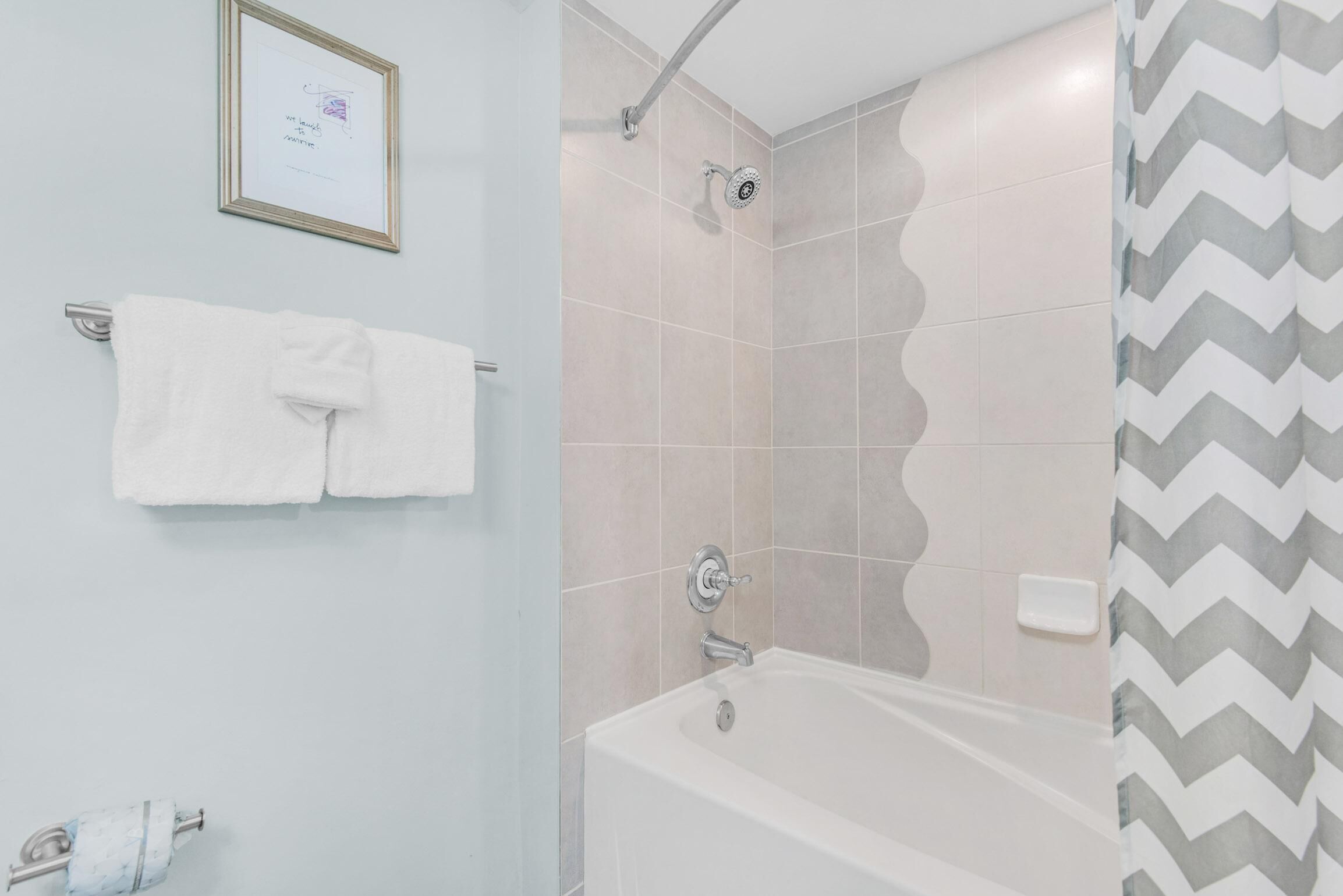 A bathroom with a bathtub, a shower, and a towel rack with two towels.