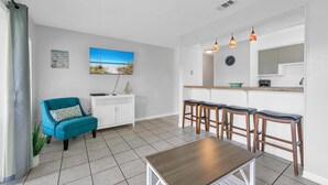 A modern kitchen with a wooden table, bar stools, and a large window. - Endless Summer B4 (Panama City Beach)