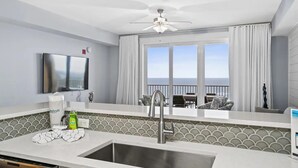 A modern kitchen with a large sink, a ceiling fan, and a view of the balcony. - Calypso 3-2210 - Love Nest (Panama City Beach)
