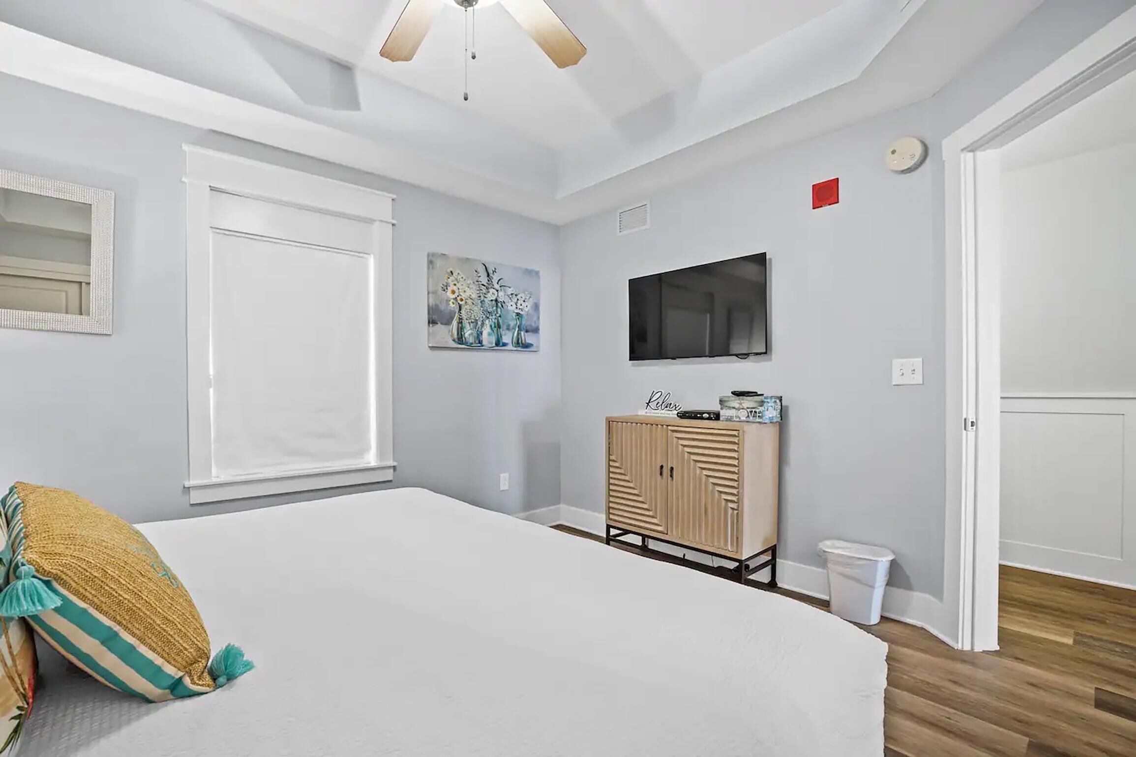 A bedroom with a bed, a TV, a cabinet, and a painting on the wall.