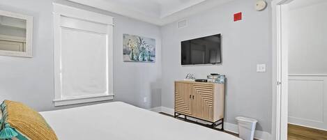 A bedroom with a bed, a TV, a cabinet, and a painting on the wall.