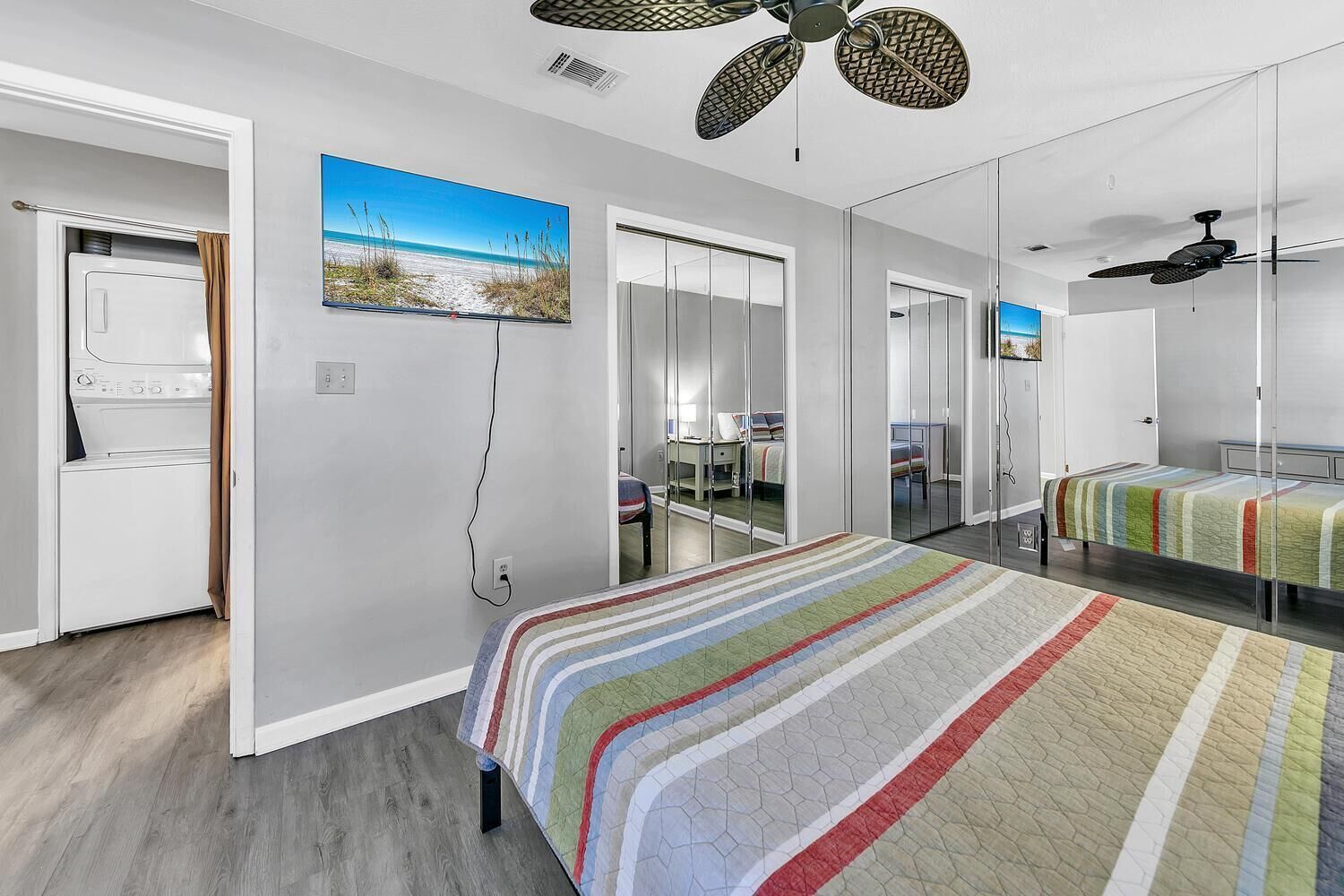 A bedroom with a bed, a dresser, a mirror, and a ceiling fan.
