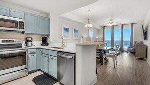 A modern kitchen with stainless steel appliances, light blue cabinets, and a central island with seating. - Calypso 3-1511 (Panama City Beach)