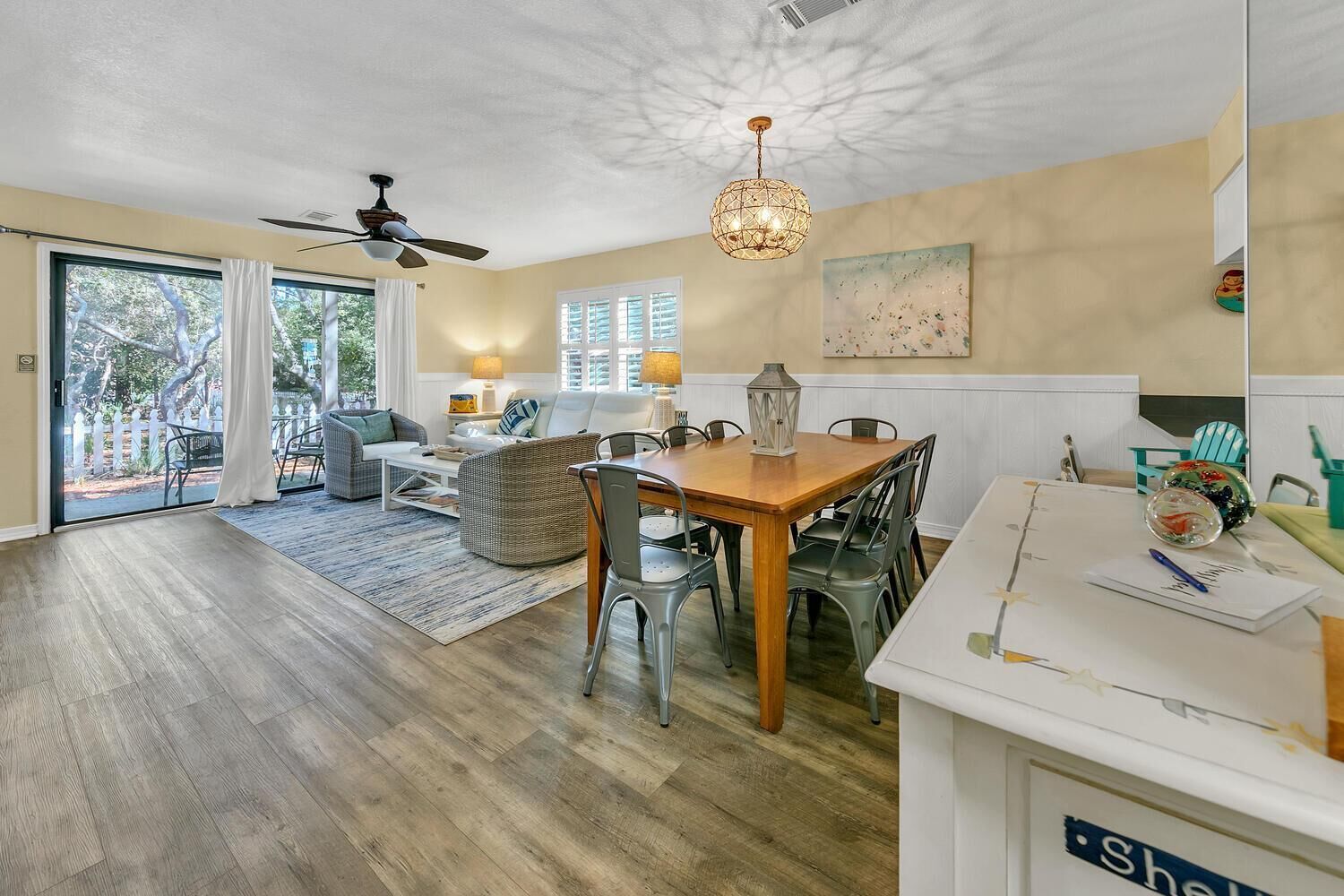 A spacious living area with a dining table, chairs, and a ceiling fan.
