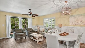 A spacious living room with a dining area, a ceiling fan, and a chandelier. - Cassine Gardens 212 (Santa Rosa Beach)