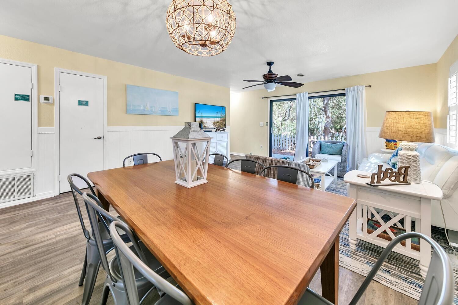 A dining area with a wooden table, chairs, a lantern, and a ceiling fan.