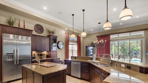 A modern kitchen with granite countertops, stainless steel appliances, and pendant lighting. - Sunny Days (Destin)