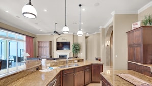 A spacious kitchen with granite countertops, dark wooden cabinets, and a large island. - Sunny Days (Destin)