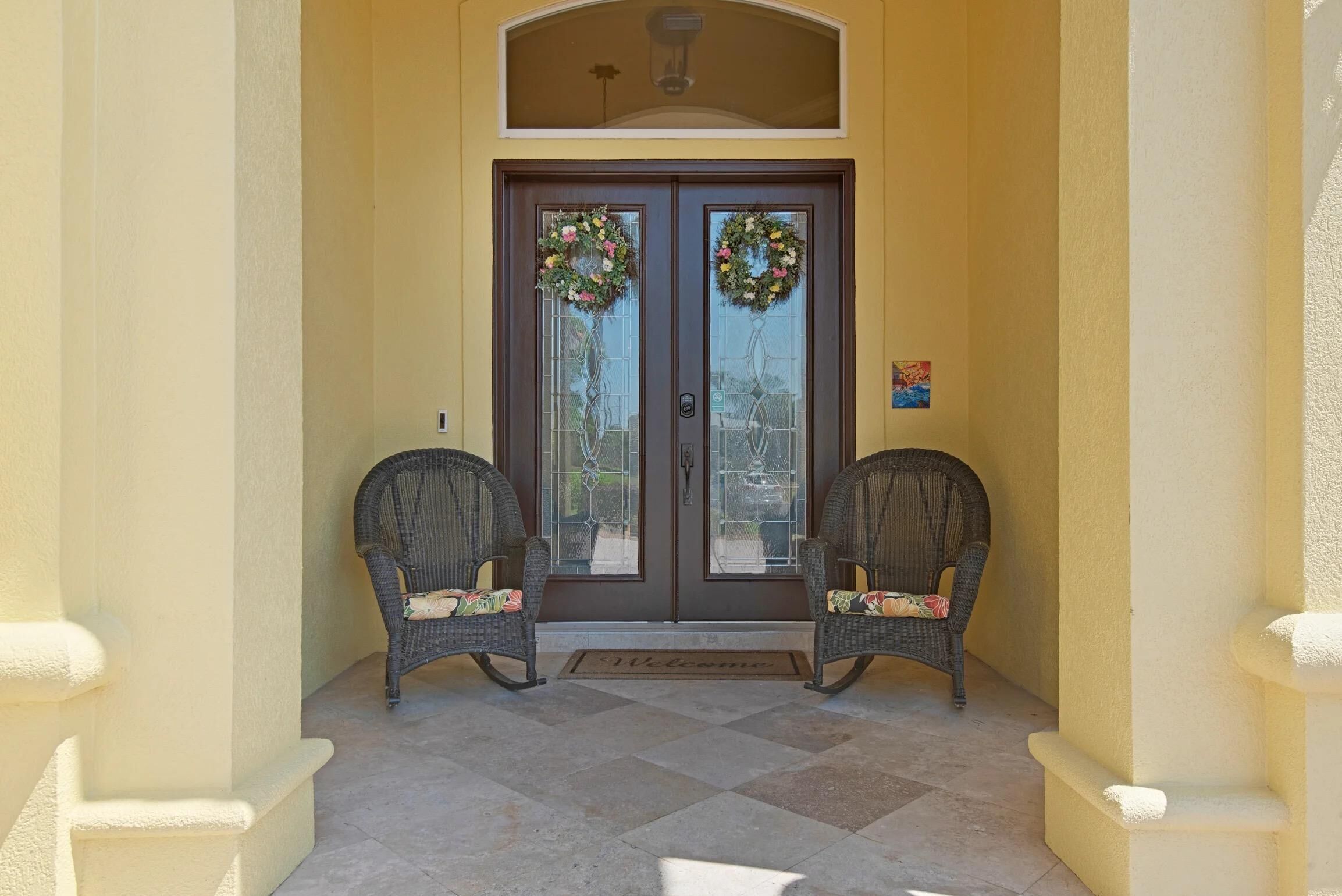A double door with glass panels and two wicker chairs with cushions in front.