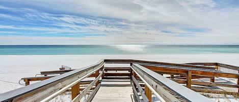 A wooden boardwalk leading to a beach with clear skies.