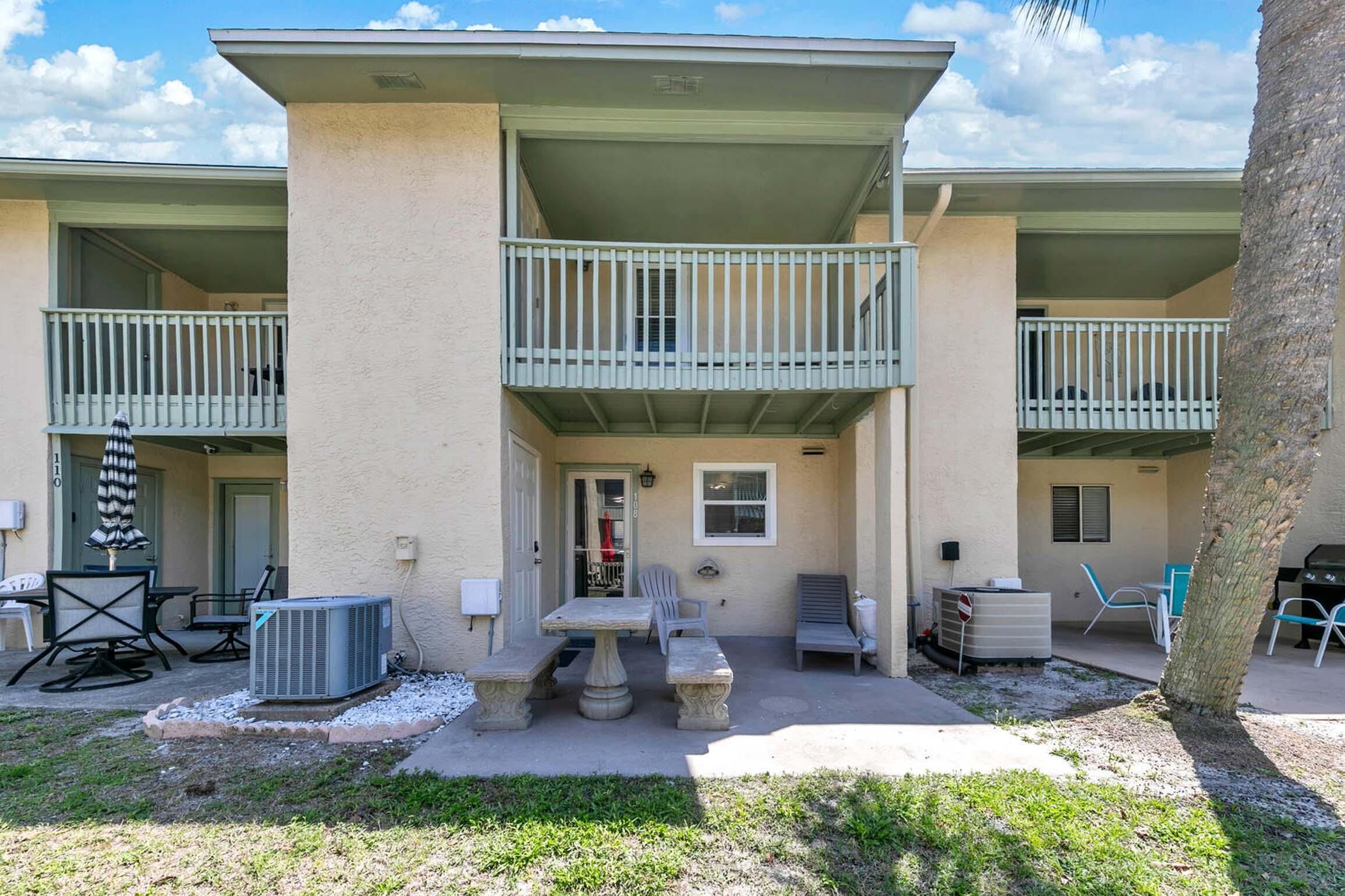 A two-story building with balconies, outdoor seating, and a grill area.