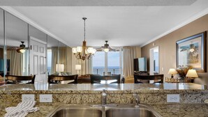 A modern kitchen with granite countertops, stainless steel sinks, and a chandelier. - Emerald Beach 930 (Panama City Beach)