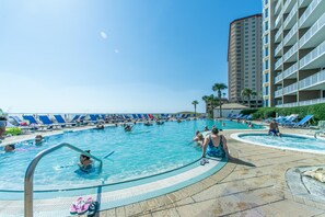 Ein Poolbereich mit Liegestühlen und einem hohen Gebäude im Hintergrund.