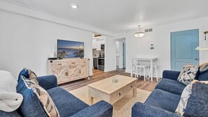 Una sala de estar moderna con un sofá azul, una mesa de centro de madera y un televisor sobre un mueble de madera.