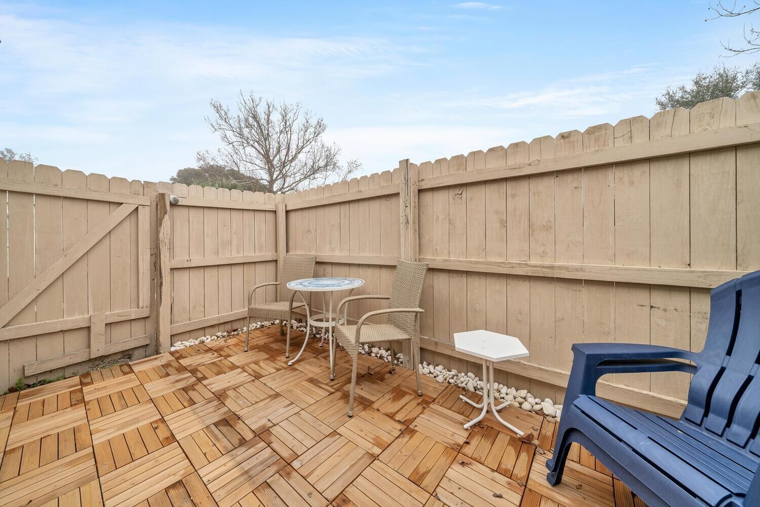 A wooden deck with a table and chairs, surrounded by a wooden fence.