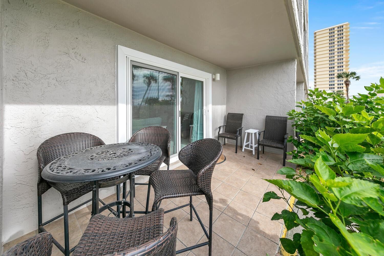 A balcony with wicker furniture, a sliding glass door, and a view of a tall building.