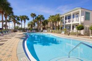 Relax by the resort pool surrounded by palm trees and lounge chairs.