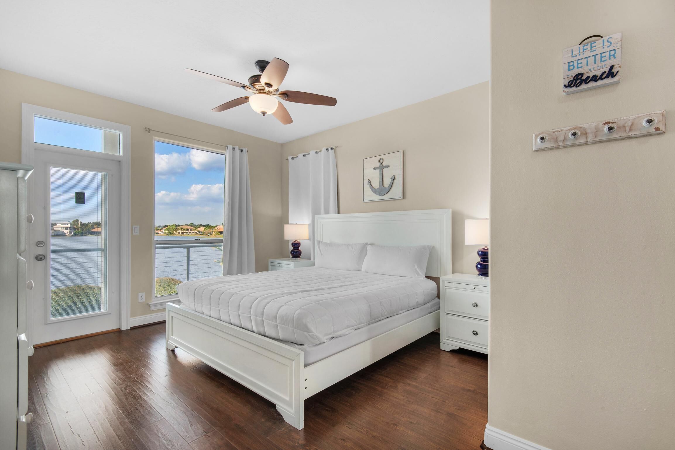 A bedroom with a bed, a ceiling fan, a view of the outdoors, and a sign on the wall.