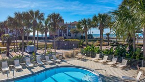 A pool area with lounge chairs and palm trees, overlooking a beach and ocean. - Destiny Beach Villas #11a&b- Beach Oasis (Destin)