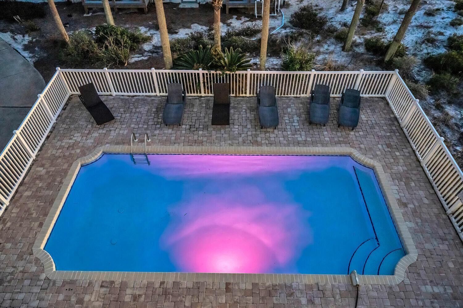 Et udendørs swimmingpool med hvide hegn og liggestole.